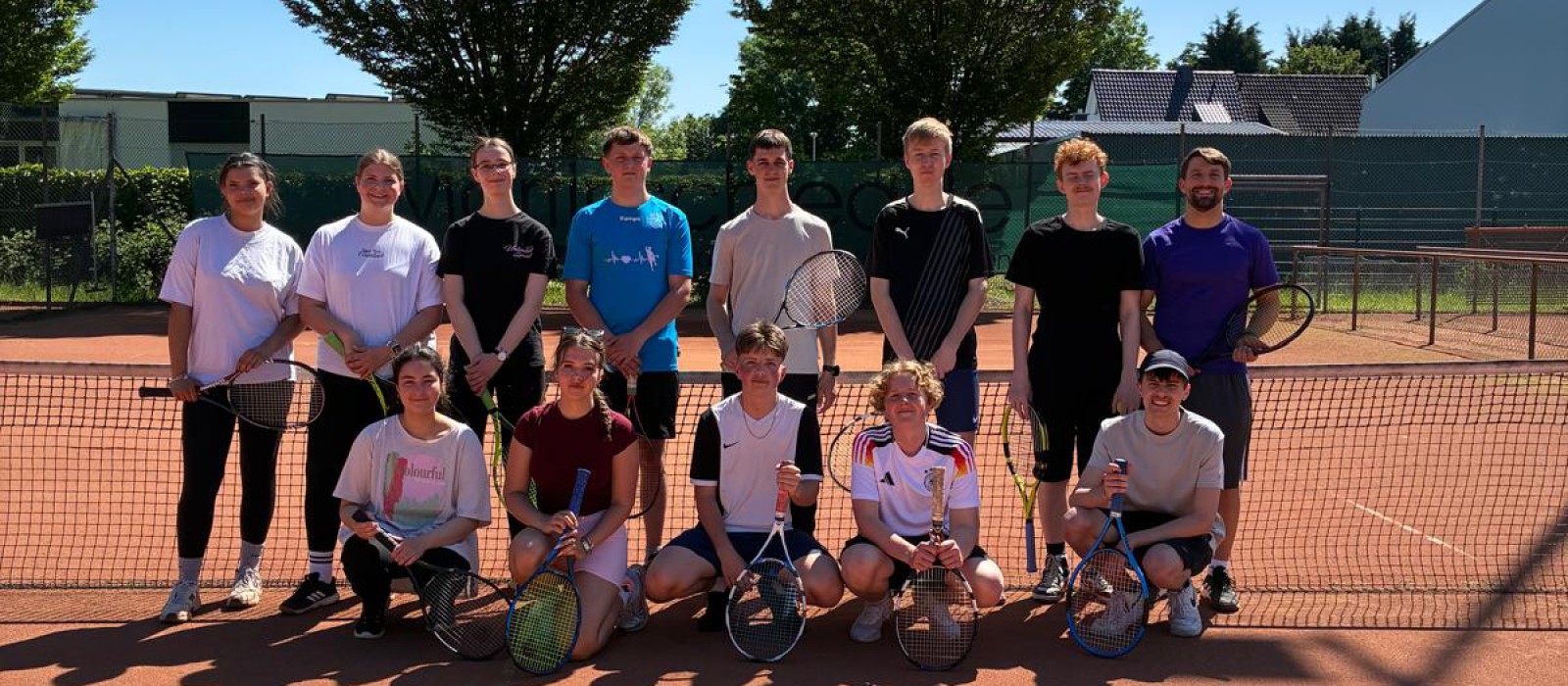 Gruppe Schüler posiert für ein Gruppenfoto auf einem Tennisplatz