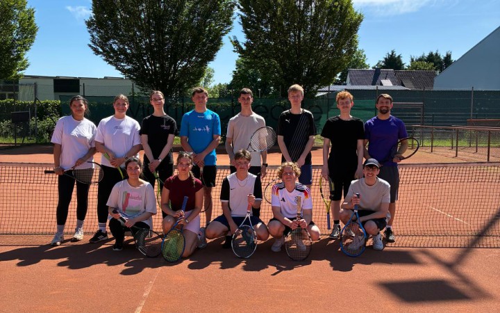 Gruppe Schüler posiert für ein Gruppenfoto auf einem Tennisplatz
