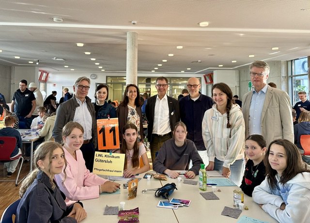 Schülerinnen und Schüler sowie Vertreter der Schulleitung stehen um eine Station bei der Probierwerkstatt.