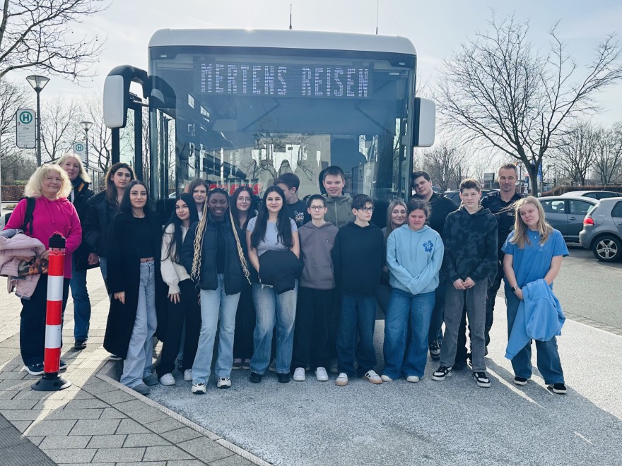 Die neu ausgebildeten Fahrzeugbegleiterinnen und Fahrzeugbegleiter mit ihren Ausbildern vor einem Bus