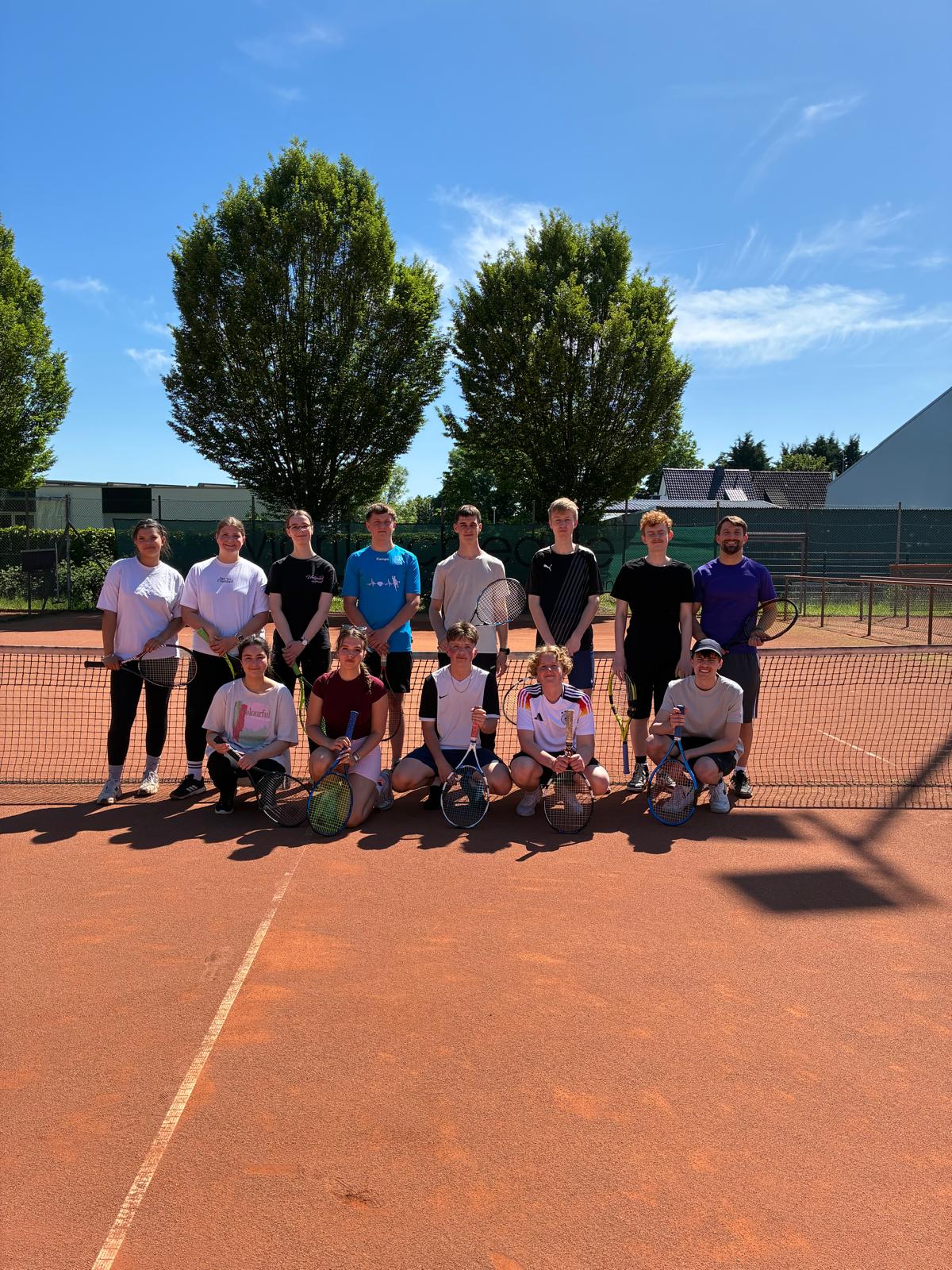 Gruppe Schüler posiert für ein Gruppenfoto auf einem Tennisplatz